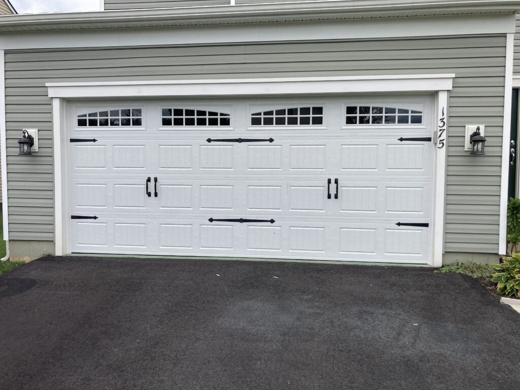 White carriage garage doors with arched windows and black handles